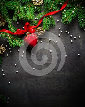 Christmas and New Year background. Christmas tree branch on a black background. Cones and fur-tree toys. View from above.