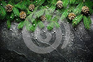 Christmas and New Year background. Christmas tree branch on a black background. Cones and fur-tree toys. View from above.