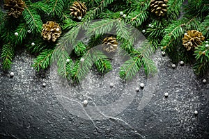 Christmas and New Year background. Christmas tree branch on a black background. Cones and fur-tree toys. View from above.