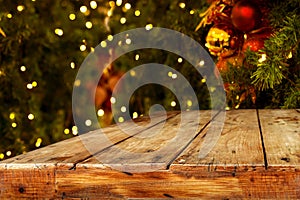 Christmas and New year background with empty dark wooden deck table over christmas tree and blurred light bokeh.