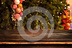 Christmas and New year background with empty dark wooden deck table over christmas tree and blurred light bokeh