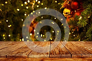 Christmas and New year background with empty dark wooden deck table over christmas tree and blurred light bokeh. photo