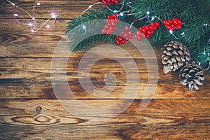 Christmas, new year background, fir branches, light garland and cones on old wooden table