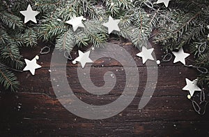 Christmas or New Year background: fur-tree branches, decoration and glittering stars on wood, top view, copy space