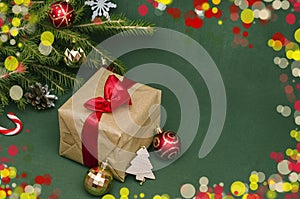 Christmas and New Year background. Gift in craft packaging with a red bow under the Christmas tree with copy space on a green