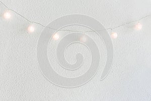 Christmas New Year Background. Hanging Pastel Golden Cotton Balls Garland White Wall Background. Scandinavian Style. Lights