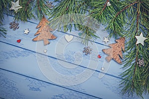 Christmas or New Year background: pine branches and few wooden decorations on the blue boards