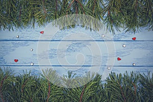 Christmas or New Year background: pine branches and small wooden hearts on the blue boards