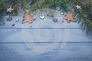 Christmas or New Year background: pine branches and some wooden decorations on the blue boards