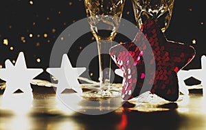 Christmas or new year background with red star decor, bokeh lights, champagne glasses. Vintage effect, selective focus