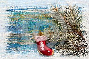 Christmas new year background. Red toy sock Santa Claus on wooden background and snow-covered spruce branches. Toned. Copy space