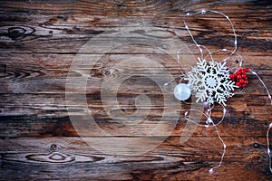 Christmas, new year background, snowflake, ball, berries, glowing garland on wooden table