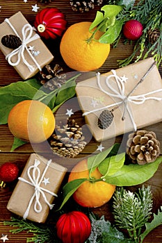 Christmas new year background with tangerines, gift boxes pine cones, winter decorations over wooden background