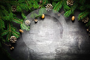 Christmas and New Year background. Christmas tree branch on a black background. Cones and fur-tree toys. View from above.