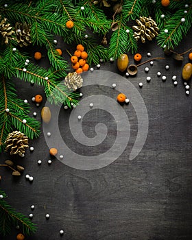 Christmas and New Year background. Christmas tree branch on a black background. Cones and fur-tree toys. View from above.