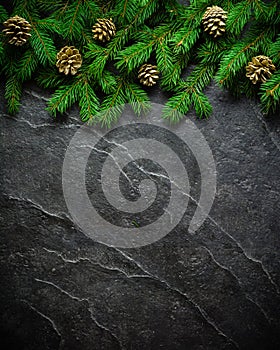 Christmas and New Year background. Christmas tree branch on a black background. Cones and fur-tree toys. View from above.