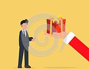 Christmas and new year. The big hand of Santa Claus is giving a businessman a red gift box for the new year and christmas