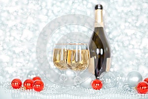 Christmas or New Year bottle of champagne, two full glasses of champagne on table, shiny and sparkling Christmas tree balls