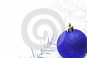 Christmas and new year card with blue ball and silver tinsel on white background. copyspace - holidays, winter and celebration con