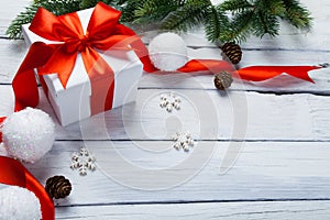 Christmas or New Year card. Gift, tree and balls decoration on white wooden background