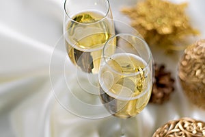 Christmas and New Year celebration with champagne. Two Champagne Glasses with Christmas decor on white fabric