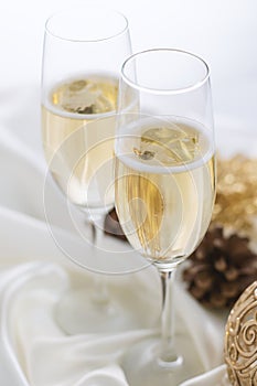 Christmas and New Year celebration with champagne. Two Champagne Glasses with Christmas decor on white fabric