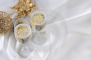 Christmas and New Year celebration with champagne. Two Champagne Glasses with Christmas decor on white fabric