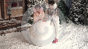 Christmas or new year. children make a snowman. two little girls make a ball of snow