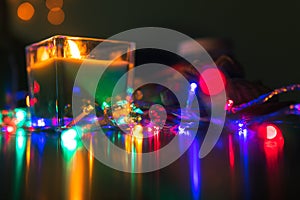 Christmas New Year Composition with candle, garlands, colorful lights, selective focus Black Background Holiday Decoration, copy