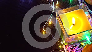 Christmas New Year Composition with candle, garlands, colorful lights, selective focus Black Background Holiday Decoration, copy