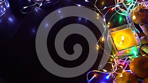 Christmas New Year Composition with candle, garlands, colorful lights, selective focus Black Background Holiday Decoration, copy