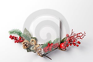 Christmas and new year composition. Creative layout made of paper blank on white background. Fir tree branches, red berry and deco