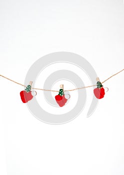 Christmas New Year composition. Garland from tiny red caps and christmas tree pins on white background