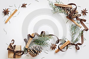 Christmas and New Year composition. Gift box with ribbon, fir branches with cones, star anise, cinnamon on white background