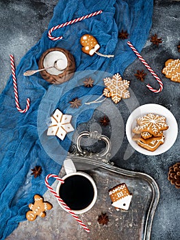 Christmas or New year composition with gingerbread, candy cane and coffee cup on dark background. Flat lay. Top view