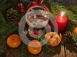 Christmas New Year composition with tangerines. red burning pine cone candle on a  wooden background.