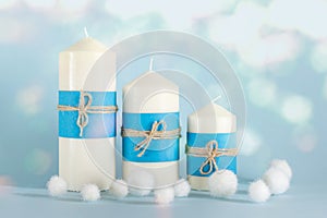 Christmas, New Year composition with three candles, blue covering and packthread bows and white balls on blue background