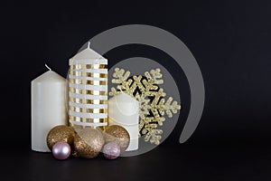 Christmas, New Year composition with candles with golden baubles and golden snowflake on black background
