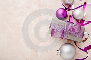 Christmas or New Year composition. Xmas purple and silver decorations: ribbons and balls on pink pastel background. Flat lay, top