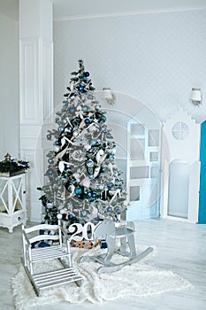 Christmas and New Year decorated interior room with presents and New year tree and toy wooden deer close up. Copy space