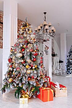 Christmas and New Year decorated interior room with red presents and New year tree in front of white wall.