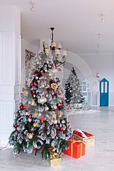 Christmas and New Year decorated interior room with red presents and New year tree in front of white wall.