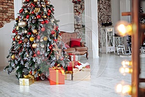 Christmas and New Year decorated interior room with red presents and New year tree and classic brown sofa in front of white wall.