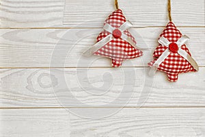 Christmas or New Year decoration background with hanging red Christmas trees on a white wooden table with copy space