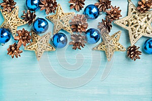 Christmas or new year decoration background: pine cones, blue glass balls, golden stars on painted backdrop, copy space