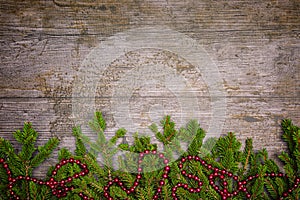 Christmas or New Year decoration background with pine twigs and a red sling on a wooden table with copy space