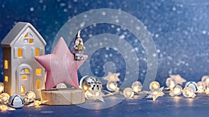 Christmas and new year decorations - wooden star with gnome and illuminated toy house with festive lights