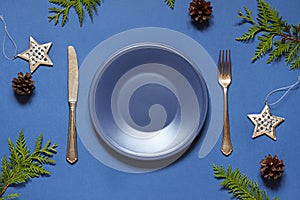 Christmas New Year empty plate flat lay on the blue background. Holiday table setting