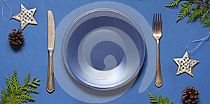 Christmas New Year empty plate flat lay on the blue background. Holiday table setting