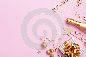 Christmas or New year festive background. Champagne bottle, gift or present box and golden confetti on pink top view. Flat lay